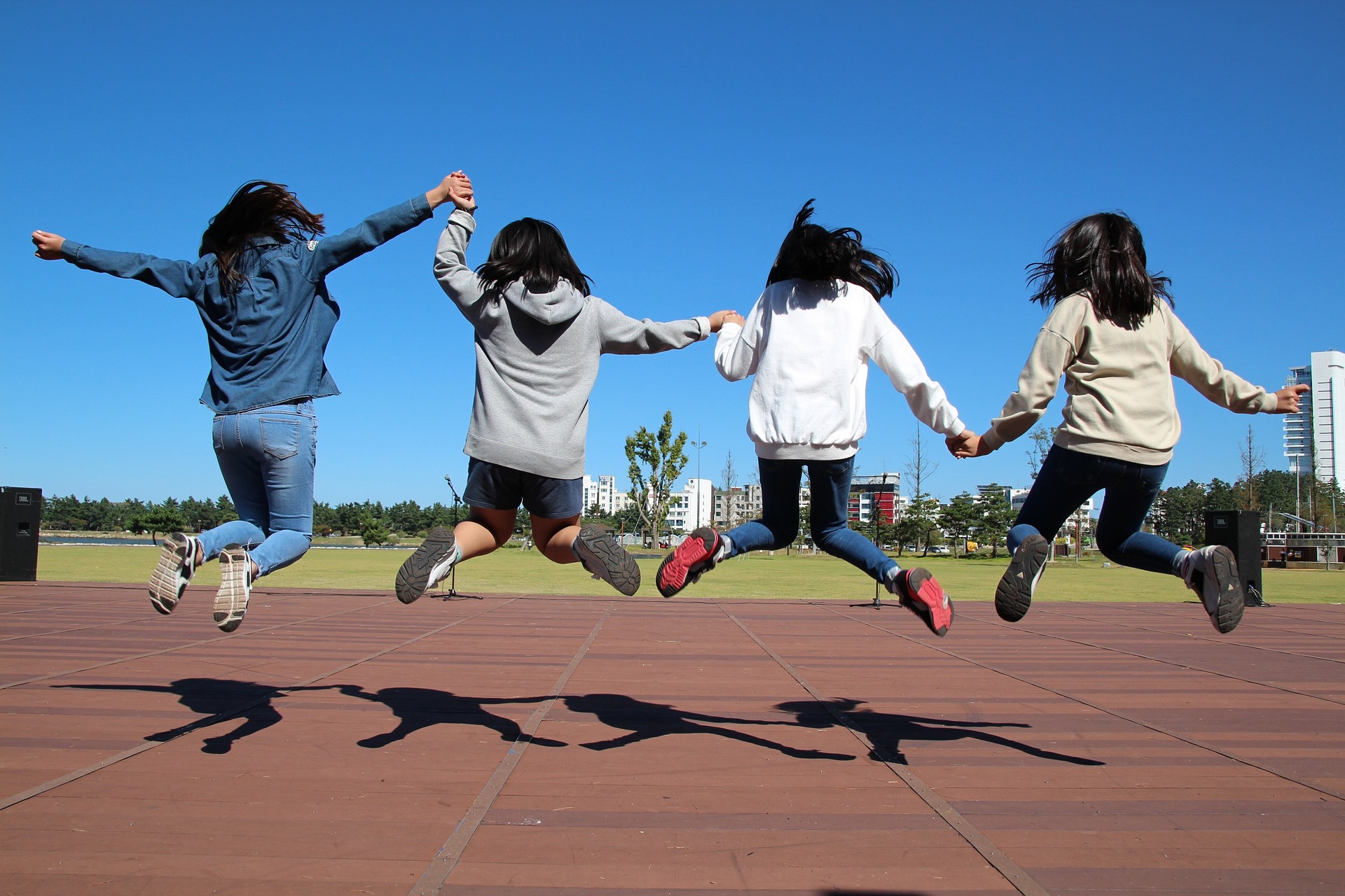 Nuoret hyppäävät yhdessä ilmaan käsistä pitäen